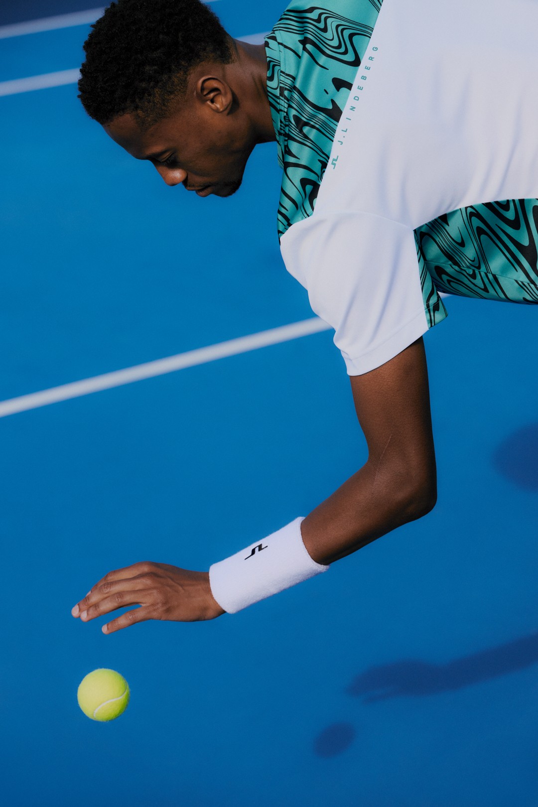 Tennis player bouncing a ball on a blue court