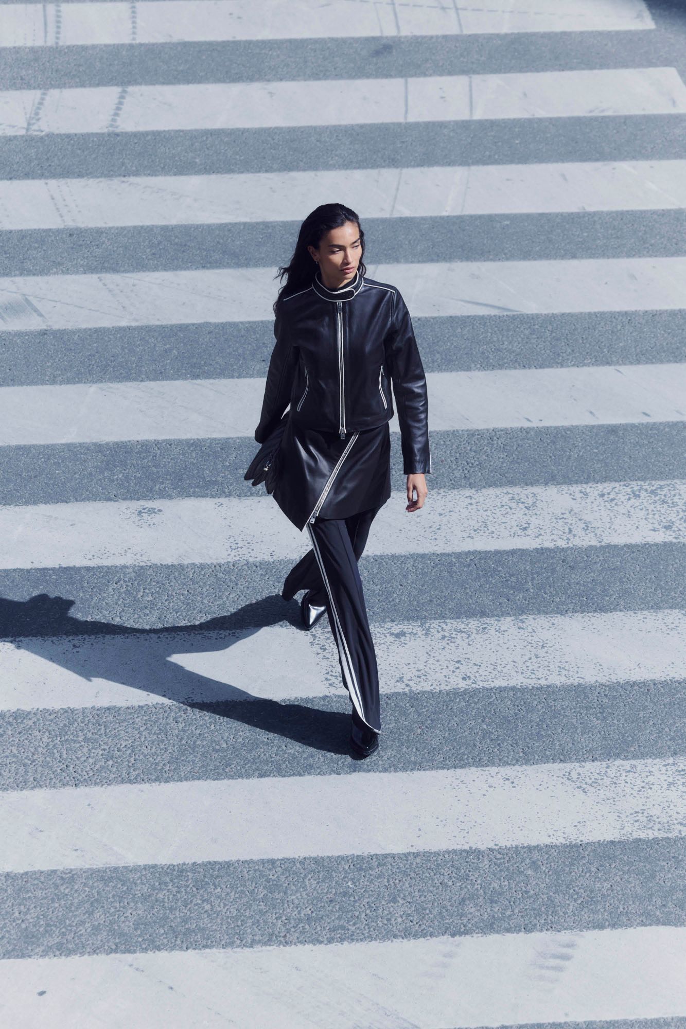 Kelly Gale crossing a street in a black leather jacket