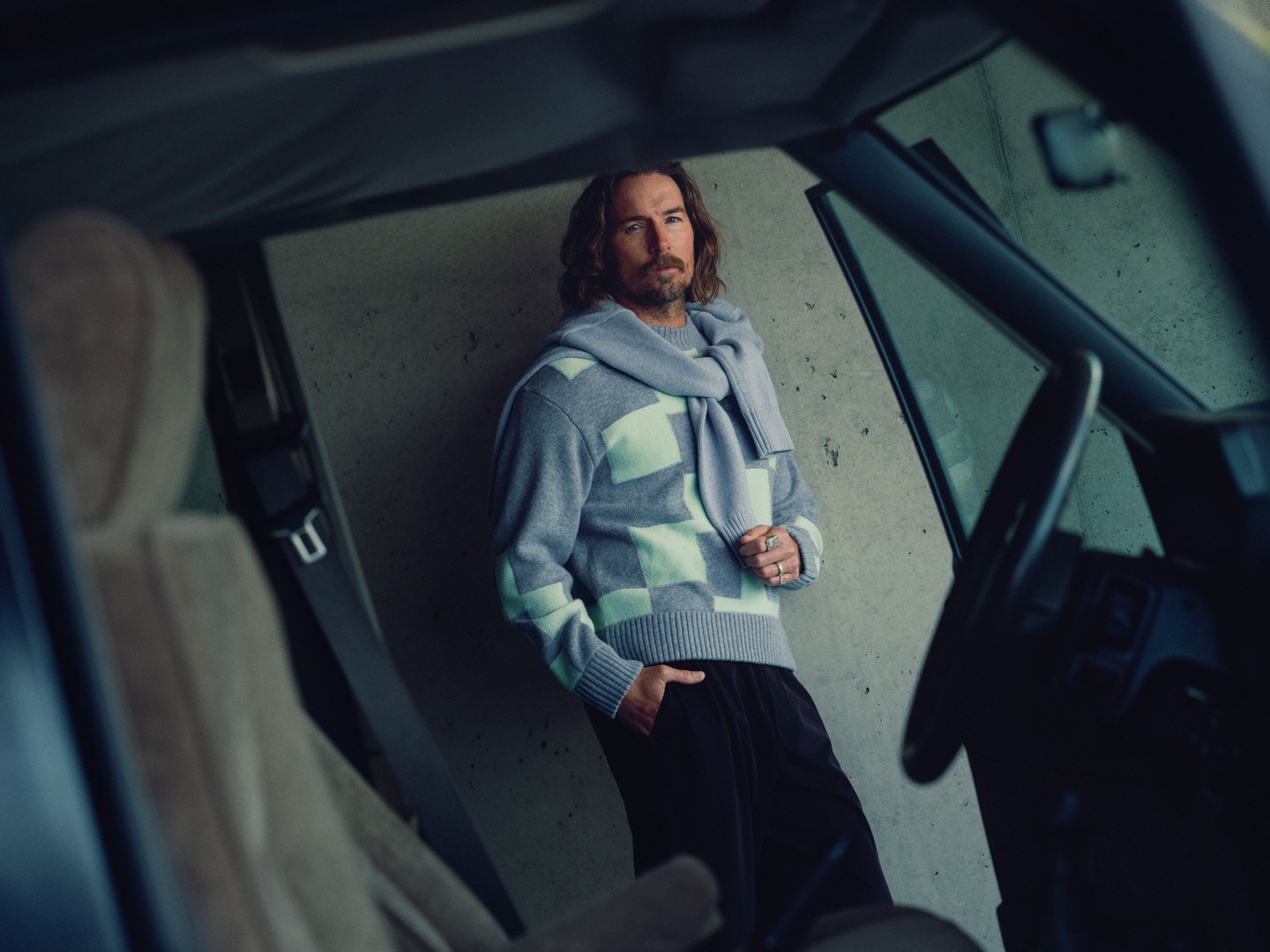 Man in a grey patterned J.LINDEBERG knit seen through an open car door